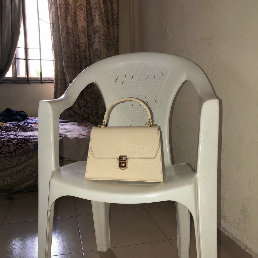 A seller’s phone photo of a cream handbag on a plastic chair